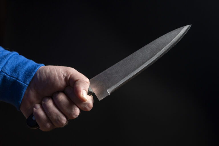 Kitchen knife in a man's hand close-up on a black background