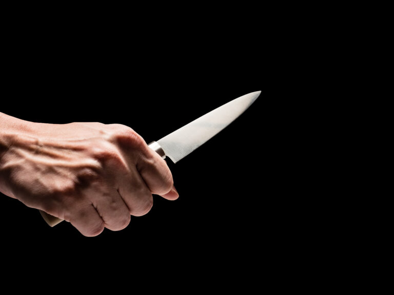 Male hand holding knife on black background